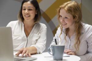 Two female HR and a manager sitting side by side happy while using an LMS