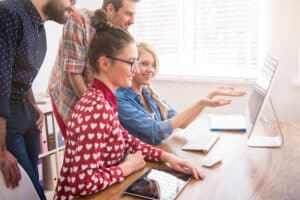 colleagues working at office while they educate each other Teach 1 Thing Approach